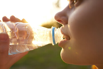 woman outdoors drinking water from a bottle of refreshment