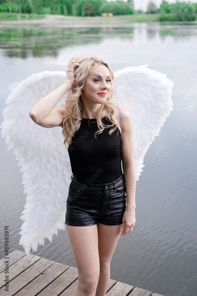 Wall mural fallen angel. girl in black with white angel wings.