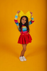 a beautiful happy dark-skinned girl in a red skirt, a colored T-shirt, a yellow bow on her head