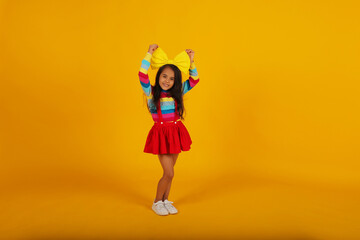 a beautiful happy dark-skinned girl in a red skirt, a colored T-shirt, a yellow bow on her head