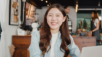 Portrait young Asia freelance lady woking feeling happy at coffee shop. Attractive Japanese businesswoman relax toothy smile looking to camera in urban cafe or restaurant with laptop.