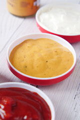 close up of Mustard, mayonnaise and sauce in a container on table .