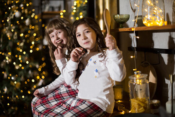 Two Kids sisters eat Christmas cookies  in the kitchen at home. 
