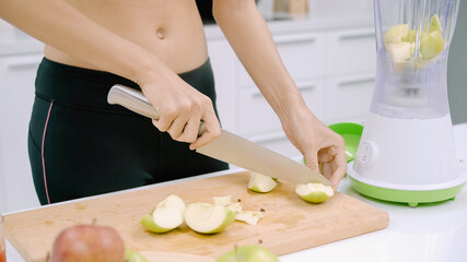 Sporty Asian woman prepare ingredient for make apple juice in the kitchen, female in sport clothing use organic fruit lots of nutrition making apple juice by herself at home. Healthy food concept.