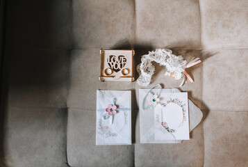 Wedding details and accessories for the bride: invitation, envelope, rings, garter, wooden box. Photography, concept, morning preparation.
