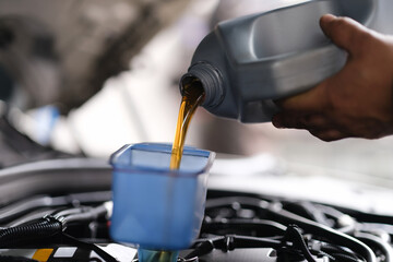 Repairman pouring motor oil into car engine closeup