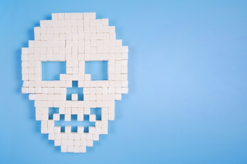 Fototapeta premium A skull made of sugar cubes on a blue medical background.Unhealthy concept of sugar addiction, obesity and related diseases, diabetes, sweet poison, articles about the dangers of sugar.Copyspace