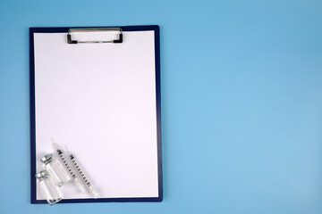 Empty ampoules, insulin syringes, a tablet with a blank page on a blue background. Medical diagnosis or a mock-up of a doctor's prescription.The concept of vaccination, diabetes mellitus, insulin.