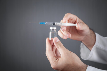 Medical doctor holds syringe and vaccine.