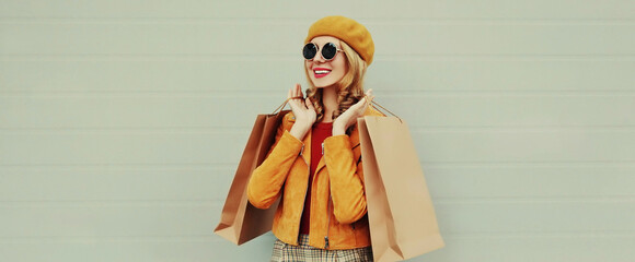 Autumn portrait of beautiful happy smiling young woman with shopping bags wearing an yellow jacket,...