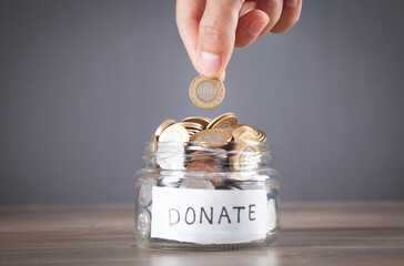 Male hand putting coin into Donation jar.