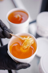 Professional Sugar paste for epilation close-up. Shugaring procedure in spa salon. Spatula. Hair removal with wax at home. Copy space background banner. Sweet honey composition close-up