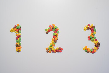 Numeral One hundred twenty three from sweet pastry topping in the form of colorful foliage on a white background.