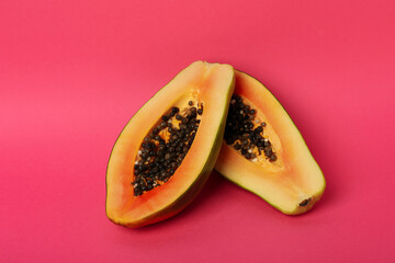 Halves of ripe papaya on pink background