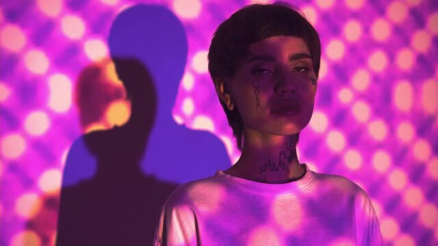 Tattooed woman looking at camera on abstract purple background 