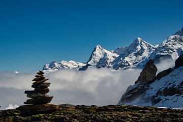 Stone men in the snowy swiss mountains with sea of fog and blue sky 