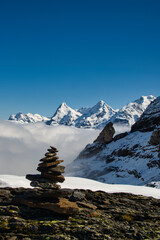 Stone men in the snowy swiss mountains with sea of fog and blue sky 