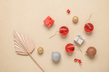 Christmas composition. Dry palm leaf, Christmas balls and gift boxes on a beige concrete background. Top view, flat lay,