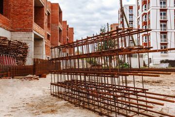 Fototapeta na wymiar Metal construction fittings on the ground at construction site on background of brick high-rises 
