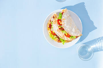 corn tortilla stuffed with meat and vegetables on a blue background. Taco
