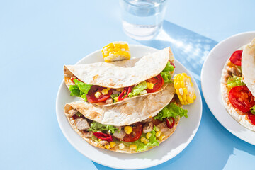 corn tortilla stuffed with meat and vegetables on a blue background. Taco