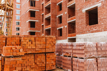 Bricks on a pallet on a construction site on a background of a brick structure