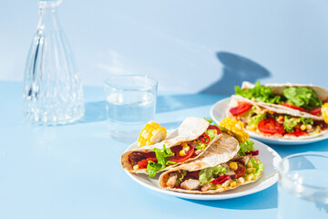 corn tortilla stuffed with meat and vegetables on a blue background. Taco