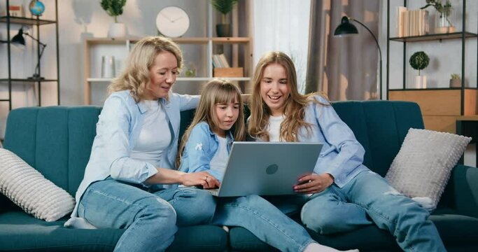 Family concept where beautiful emotional happy smiling mother and her two daughters have pleasant video chat with relatives on computer at home ,front view