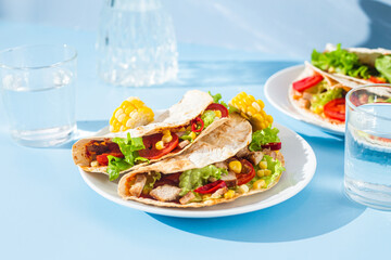 corn tortilla stuffed with meat and vegetables on a blue background. Taco