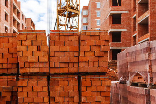 Bricks pallet on construction site on  background of a brick structure. Construction of brick houses