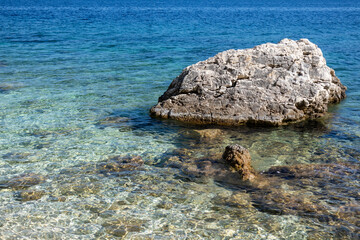 Rock in azure clear water on coast of Lefkada island in Greece. Summer wild nature vacation travel to Ionian Sea
