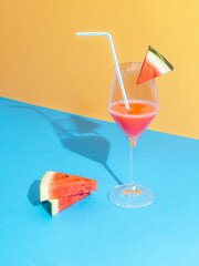 Watermelon cocktail with slices against pastel blue and baige background. Minimal nature composition. Summer sunshine shadow.