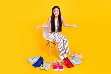 Full length body size photo girl irritated choosing shoes in fitting room unhappy isolated vivid yellow color background