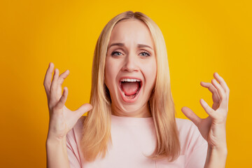 Portrait of crazy angry irritated girl shout open mouth on yellow background