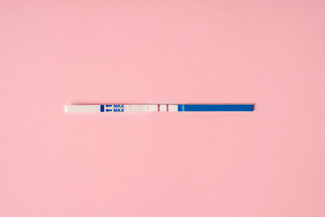 A positive pregnancy test on a pink background. Minimalism and a place for text