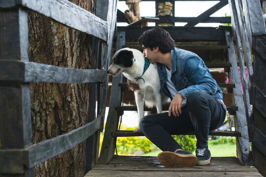 Hormonal changes in adolescence. Young man sitting on a ladder with his pet. Social adaptation problems in young people.