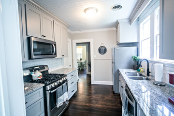 A small cottage kitchen with gray cabinets and dark hardwood floors in a short-term rental house