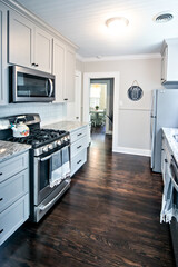 A small cottage kitchen with gray cabinets and dark hardwood floors in a short-term rental house