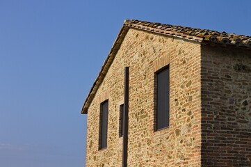 The facade of a stone farmhouse with two windows and a roof covered with tiles (Umbria, Italy, Europe) - 459904764