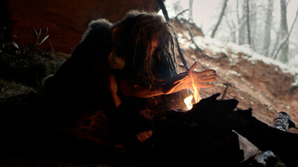 Prehistoric caveman in cave sitting by fire