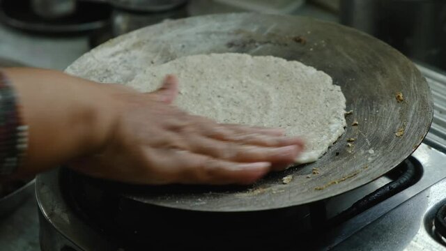 Indian woman making Bhakari ( a Maharashtrian authentic Bread ) on hot pan.