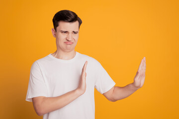 Portrait of displeased guy show refuse gesture empty space grimace on yellow background