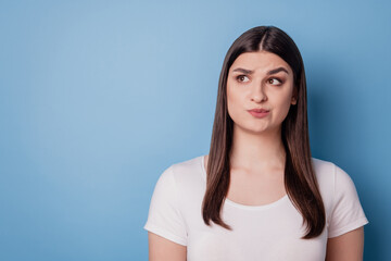 Portrait of interested uncertain lady look blank space have doubts on blue background