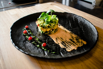 Colorful avocado tartar on a black plate at a restaurant