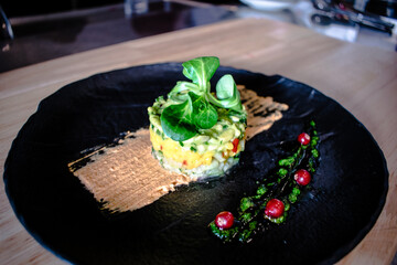 Colorful avocado tartar on a black plate at a restaurant
