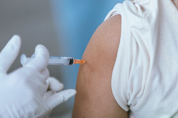 Close up Doctor injecting COVID-19 vaccine on a person's shoulder, Vaccination, immunization, disease prevention concept