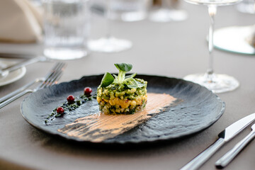 Colorful avocado tartar on a black plate at a restaurant