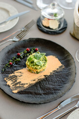 Colorful avocado tartar on a black plate at a restaurant