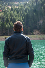 Adventurer with black jacket and brown hair looking at the lake