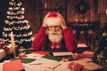 Photo of troubled overwhelmed santa claus sit workspace delivery service wear hat sweater in north...
